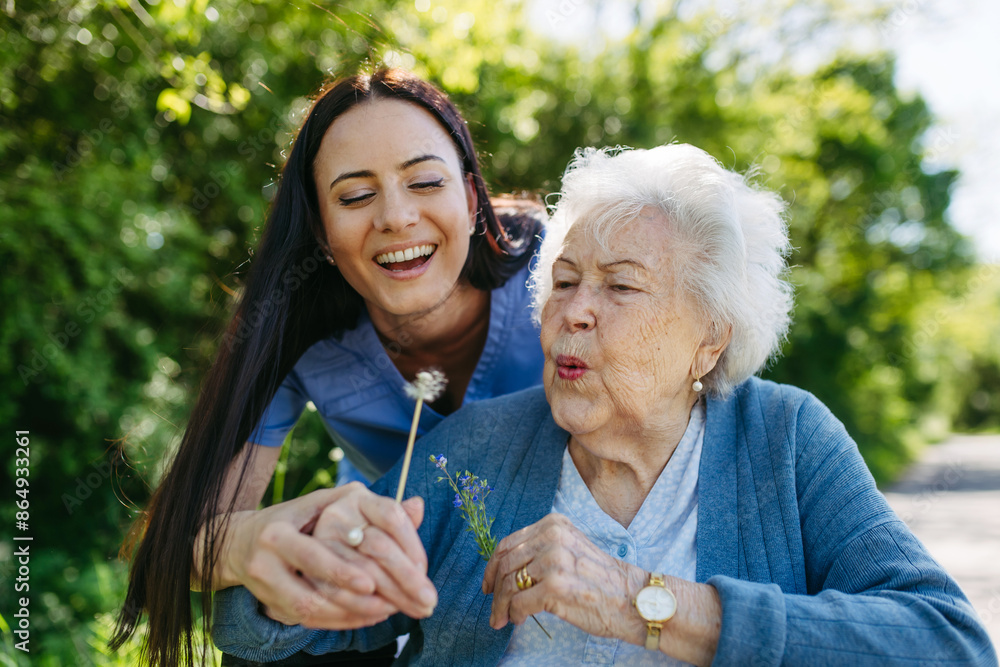 Pflegekraft und Seniorin mit einer Pusteblume